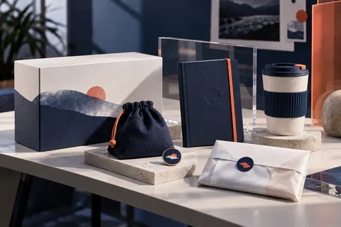 Coffret de lancement avec carnet, gobelet, pochette et invitation présentés en studio