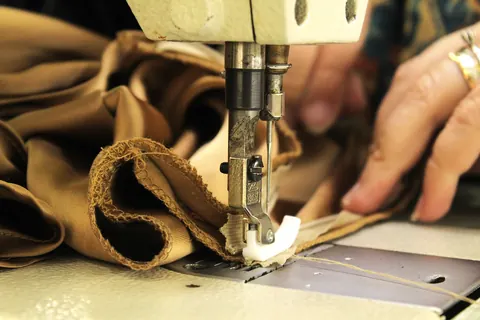 Gros plan sur des mains guidant un tissu sous une machine à coudre