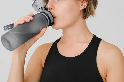 Une personne boit dans une gourde pendant une activité sportive